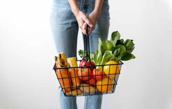 woman carrying basket of fruits and vegetables