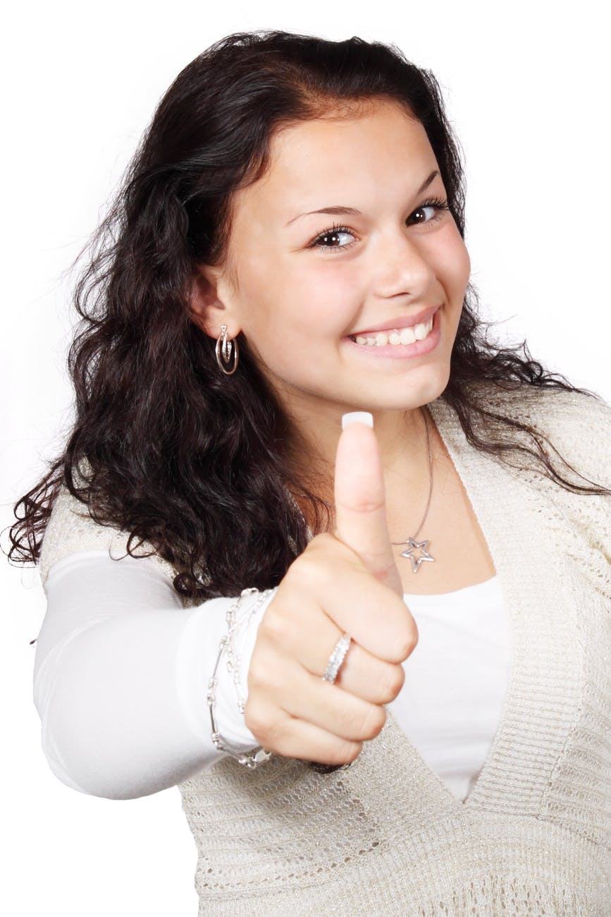 smiling woman wearing white and beige showing thumbs up