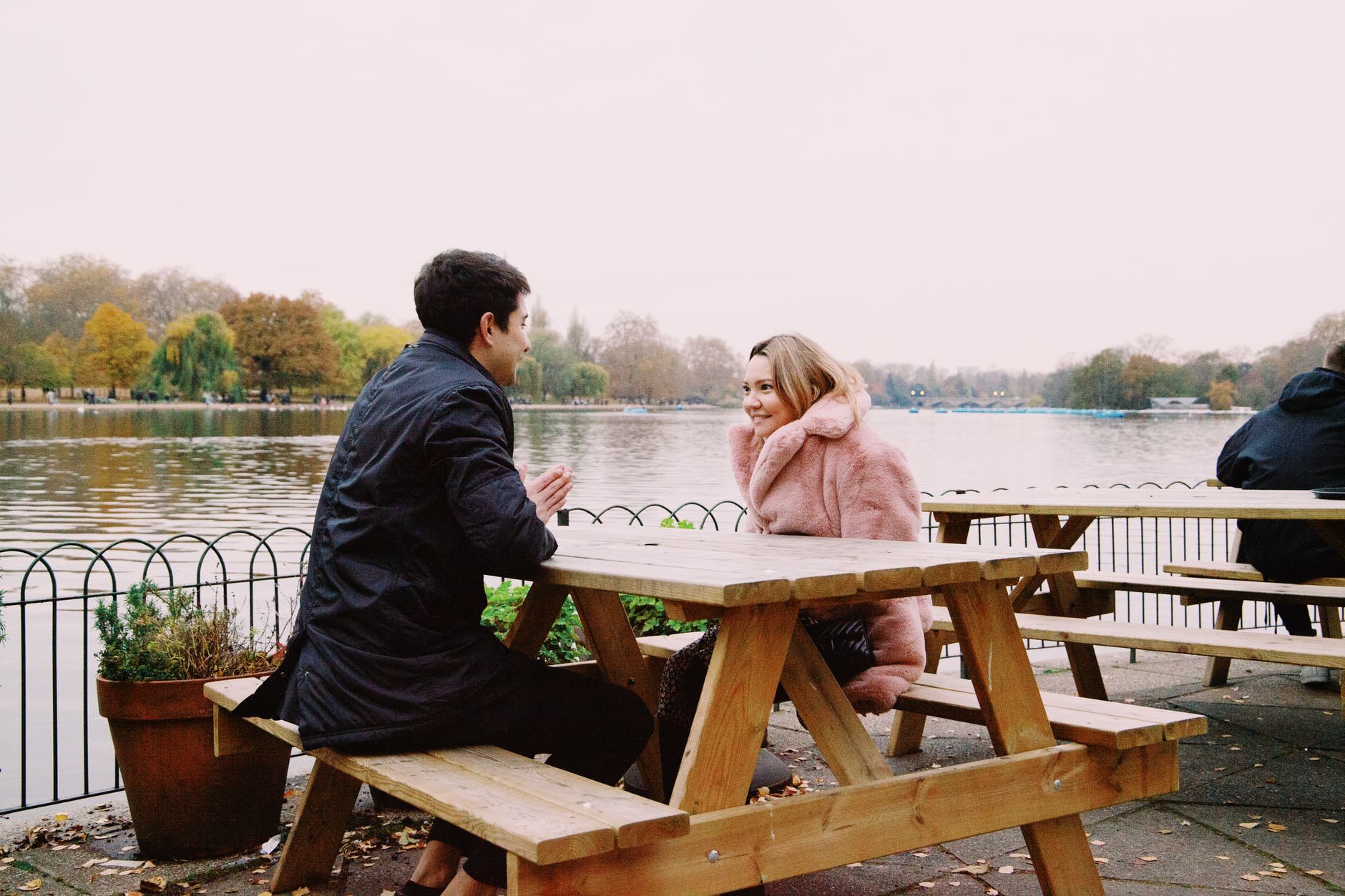 cheerful young couple resting in cafe at lakeside during romantic date on autumn day